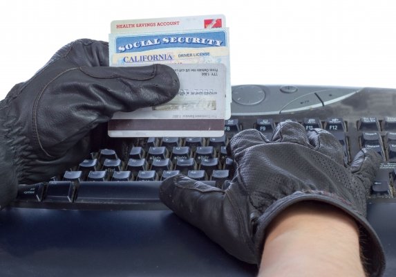 identity theft protection services hands with black gloves on computer typing social security number hands hold social security card